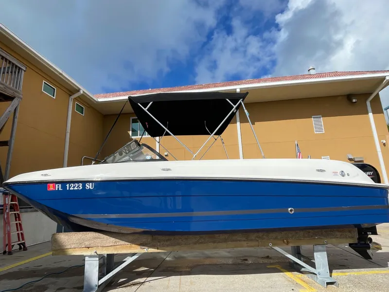 Slide: The Image of 2021 Bayliner Element E21 boat with blue hull, docked outdoors under a clear sky. - 1