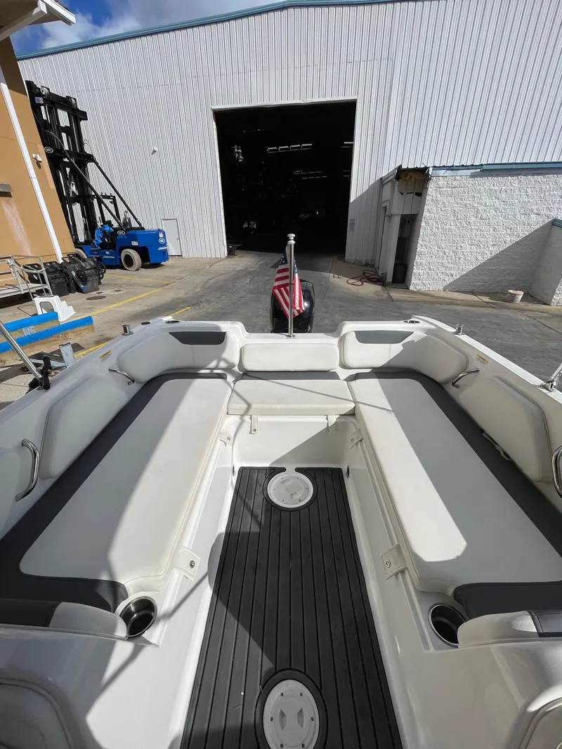 Slide: The Image of 2021 Bayliner Element E21 boat interior with seating, docked near a warehouse. - 16