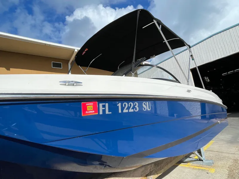 Slide: The Image of 2021 Bayliner Element E21 boat with Florida registration, docked under a clear sky. - 2