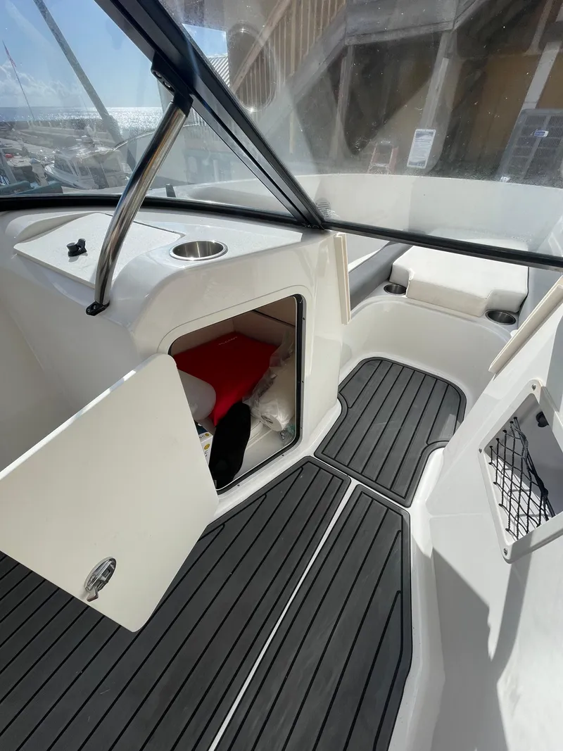 Slide: The Image of 2021 Bayliner Element E21 interior with open storage compartment and sleek black flooring. - 25