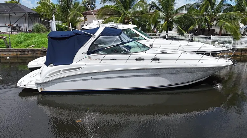 Slide: The Image of 2003 Sea Ray 360 Sundancer yacht docked by palm trees, featuring sleek design and blue canopy. - 3