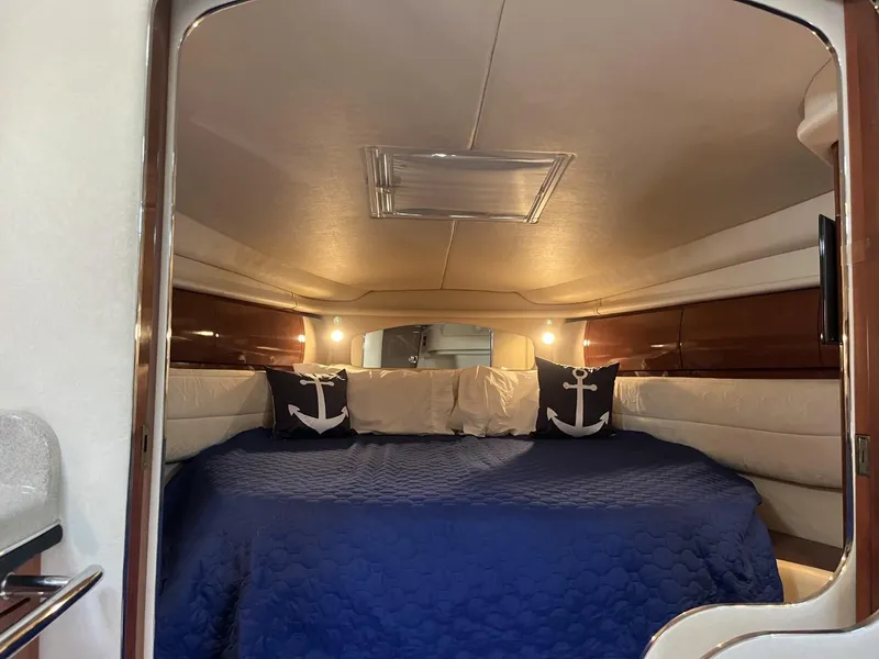 Slide: The Image of 2003 Sea Ray 360 Sundancer cabin with blue bedding and anchor-themed pillows. - 44