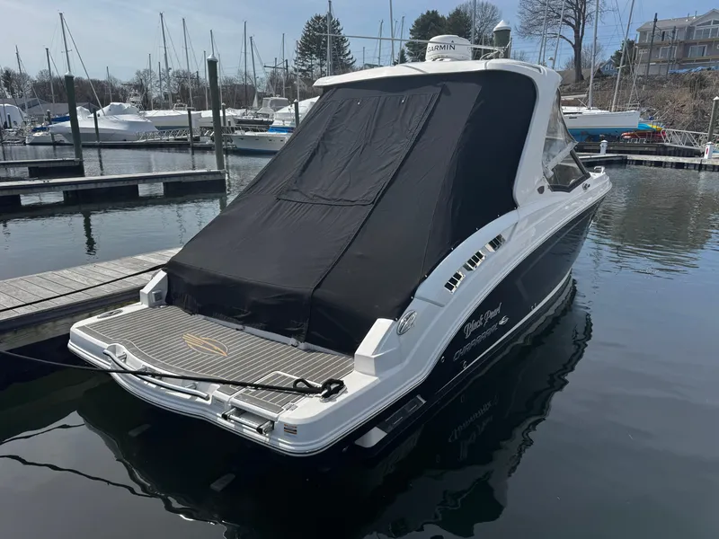 Slide: The Image of 2018 Chaparral 307 SSX boat docked with black cover, in a marina setting. - 2