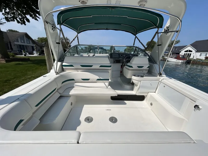 Slide: The Image of 1999 Formula 34 PC boat with spacious cockpit and green canopy, docked by waterfront homes. - 16