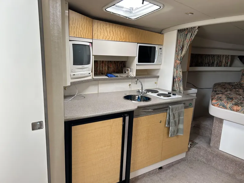 Slide: The Image of 1999 Formula 34 PC yacht interior with kitchenette, featuring sink, stove, and compact appliances. - 18
