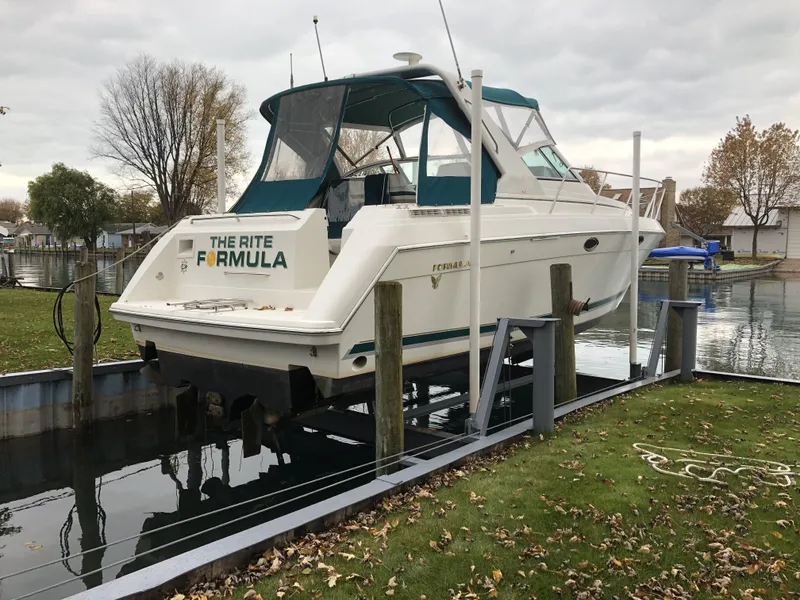 Slide: The Image of 1999 Formula 34 PC boat docked on a lift in a serene marina setting. - 4