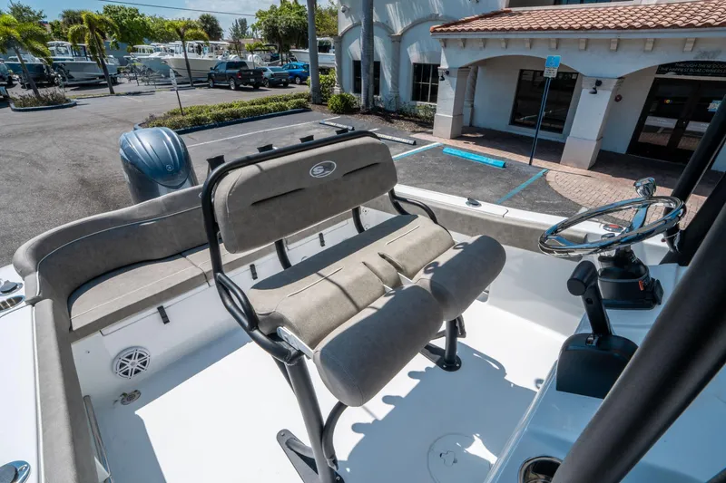 Slide: The Image of 2025 Sea Hunt Ultra 229 boat interior with seating and steering wheel in a marina setting. - 17