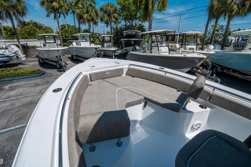 Slide: The Image of 2025 Sea Hunt Ultra 229 boat interior with seating, surrounded by palm trees and other boats. - 19