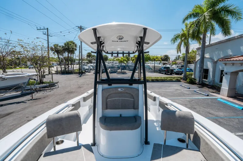 Slide: The Image of 2025 Sea Hunt Ultra 229 boat with T-top, parked outdoors under clear sky. - 22