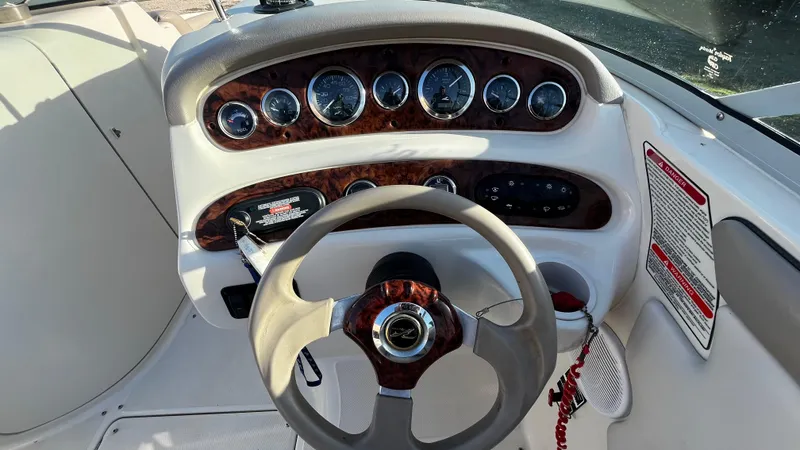 Slide: The Image of 2002 Sea Ray 270 Sundeck interior with seating and windshield, parked on grassy lot. - 10