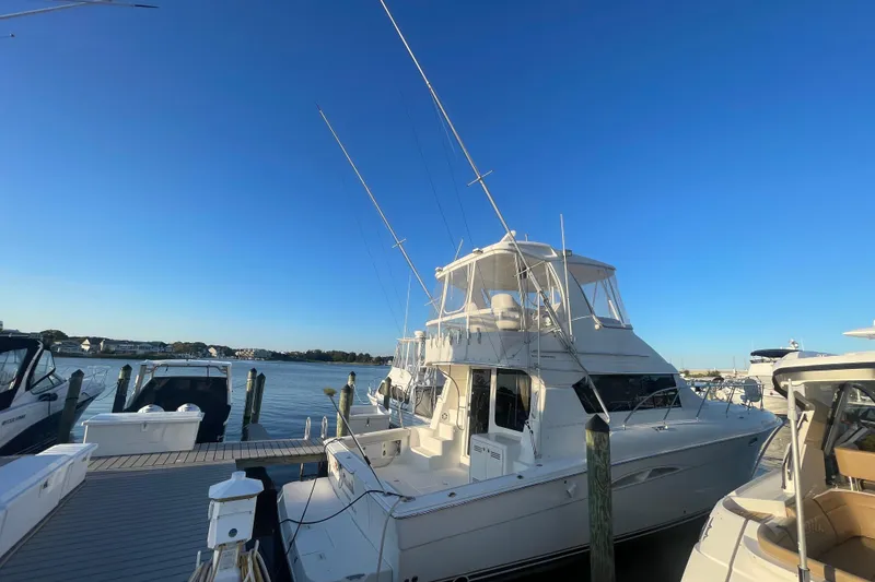 The Image of 2006 Silverton 42 Convertible yacht docked at a marina under clear blue skies. - 0