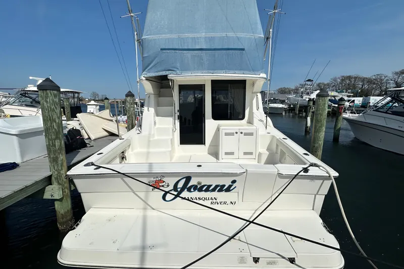 Slide: The Image of 2006 Silverton 42 Convertible boat docked at marina, rear view with blue canopy. - 13