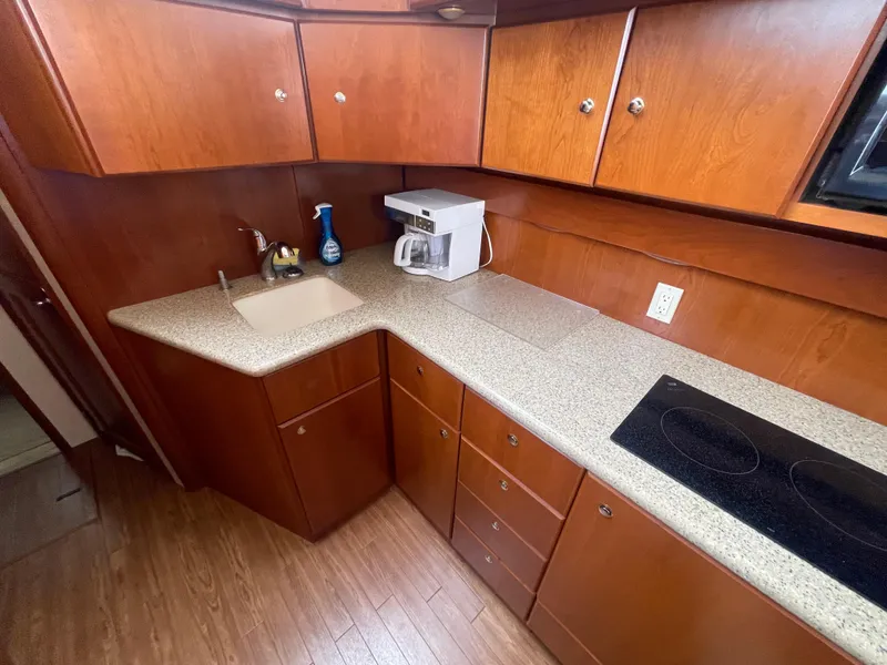Slide: The Image of 2006 Silverton 42 Convertible yacht kitchen with wood cabinets, countertop, sink, and stovetop. - 34