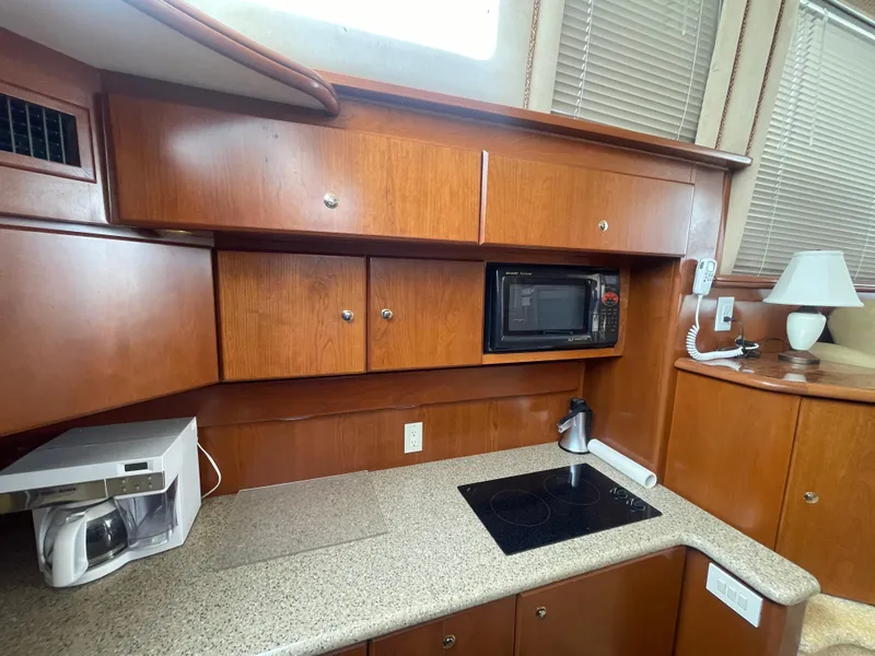 Slide: The Image of 2006 Silverton 42 Convertible yacht kitchen with microwave, stove, and wooden cabinets. - 35
