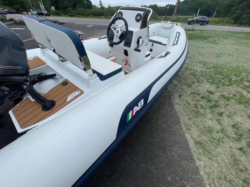 Slide: The Image of 2025 AB Inflatables Alumina 15 ALX boat, white with blue accents, parked on pavement. - 6