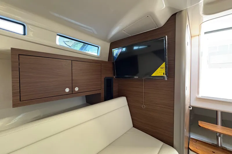 Slide: The Image of 2026 Boston Whaler 325 Conquest cabin interior with TV and wooden cabinetry. - 10