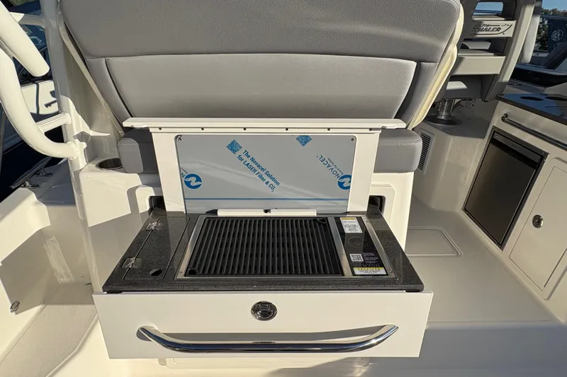 Slide: The Image of 2026 Boston Whaler 325 Conquest boat interior with built-in grill and seating. - 4