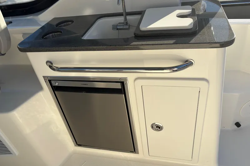 Slide: The Image of 2026 Boston Whaler 325 Conquest boat kitchenette with sink, cutting board, and mini fridge. - 6