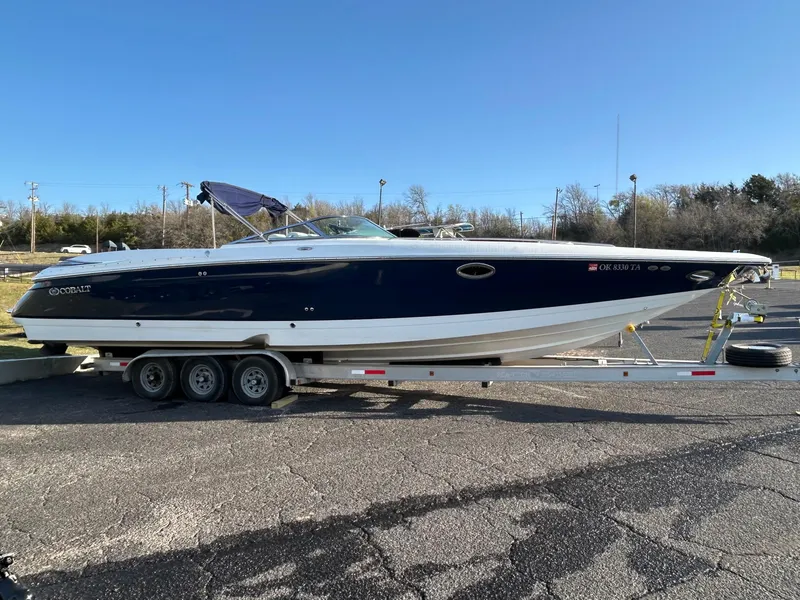 Slide: The Image of 2005 Cobalt 343 boat on trailer, parked outdoors, with blue and white exterior. - 2