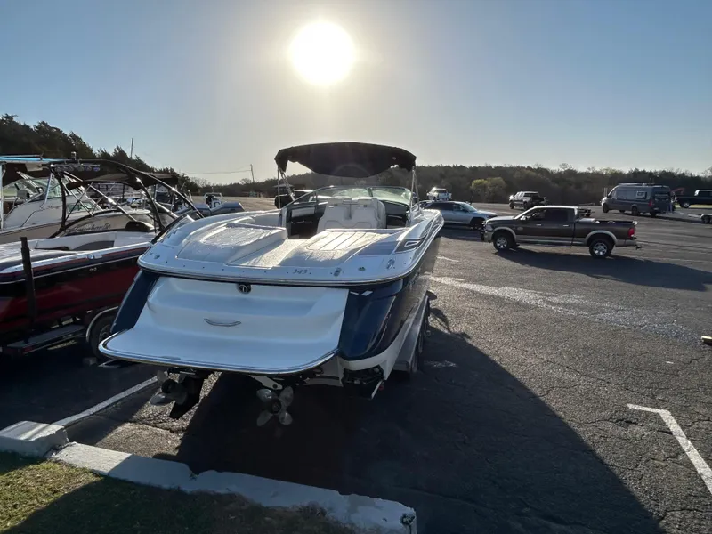 Slide: The Image of 2005 Cobalt 343 boat parked in a sunny marina with vehicles nearby. - 3