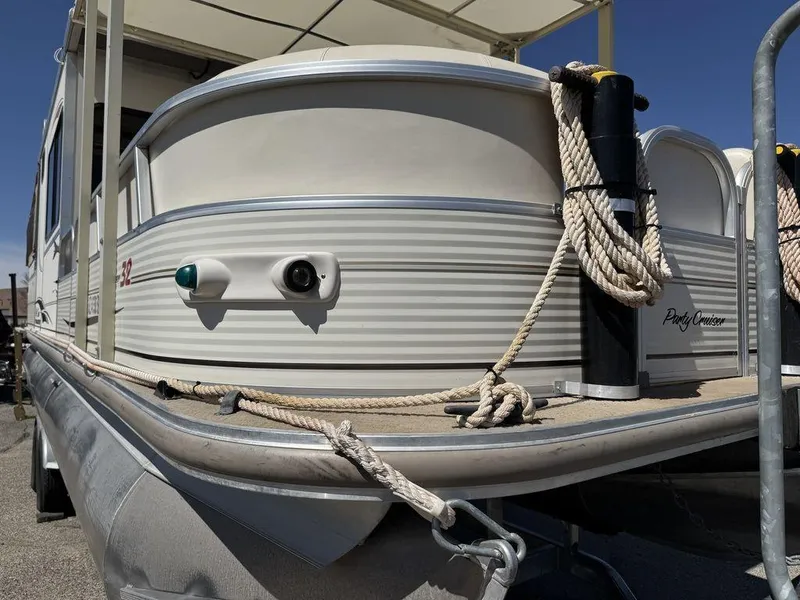 Slide: The Image of 2006 Sun Tracker Party Cruiser 32 pontoon boat with ropes, docked under clear blue sky. - 37
