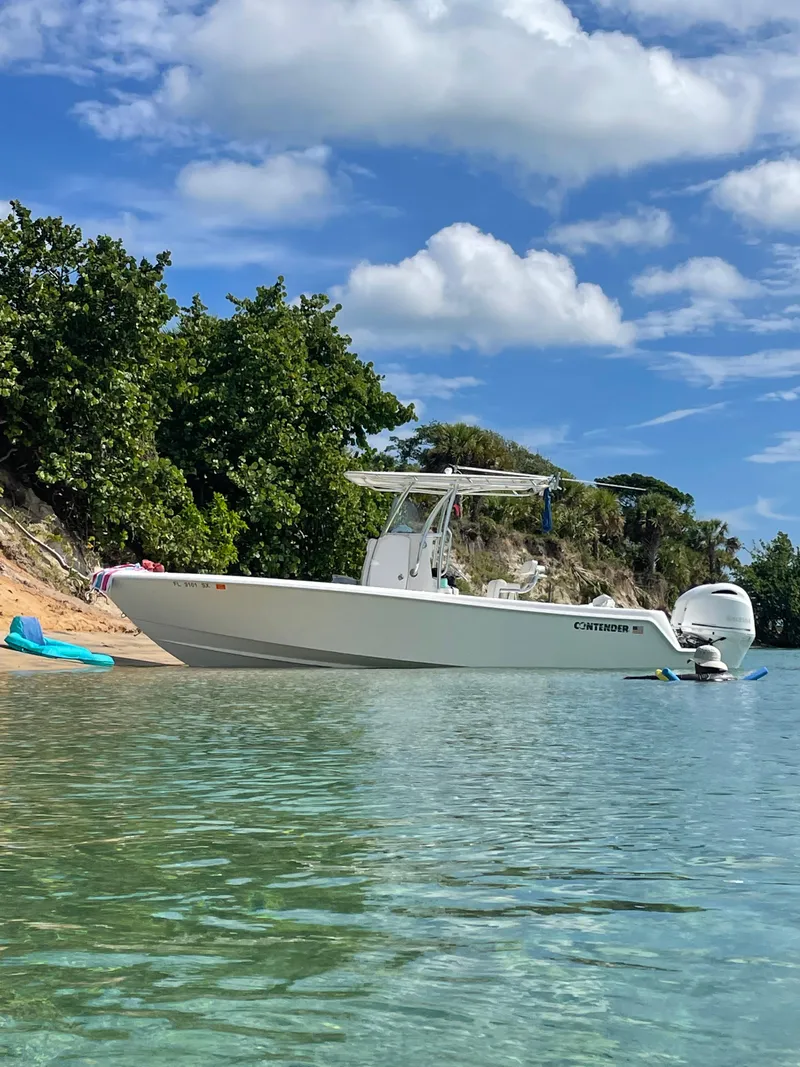 Slide: The Image of 2021 Contender Tournament boat anchored near a scenic shoreline with clear blue skies. - 1