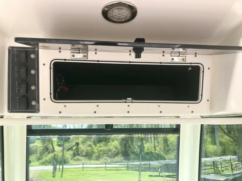 Slide: The Image of 2016 Boston Whaler OUTRAGE storage compartment with open hatch and control panel. - 15