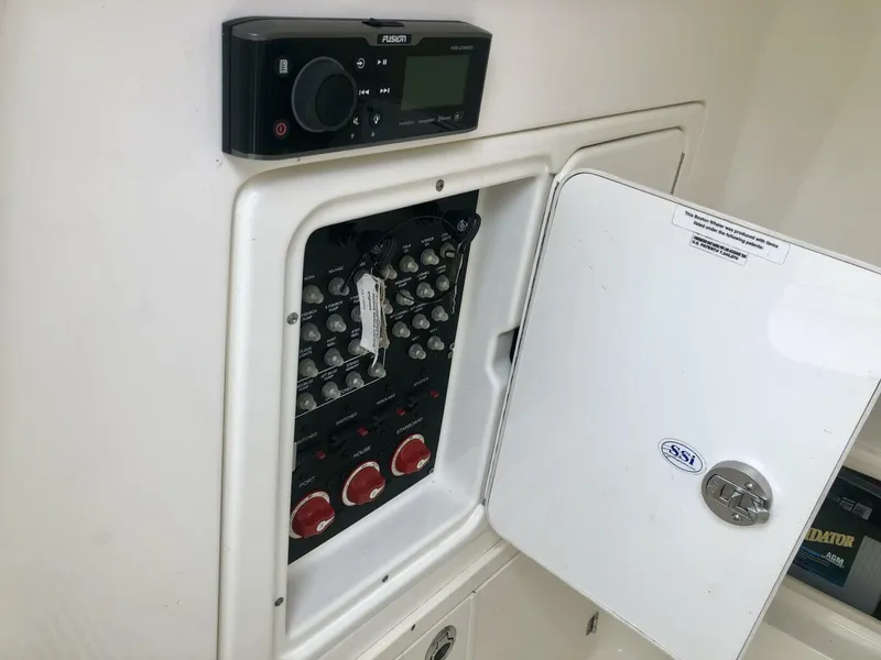 Slide: The Image of Electrical panel inside a 2016 Boston Whaler OUTRAGE boat, featuring control switches and a Fusion stereo. - 18