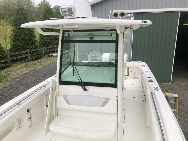 Slide: The Image of 2016 Boston Whaler OUTRAGE boat with white deck and cabin, parked near a green building. - 19