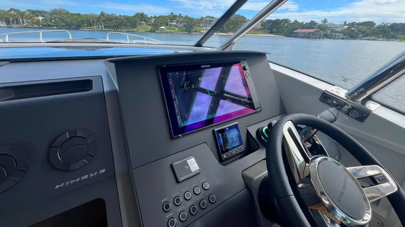 Slide: The Image of Helm of 2025 Nimbus Weekender 11 #49 with modern navigation system, steering wheel, and scenic water view. - 18