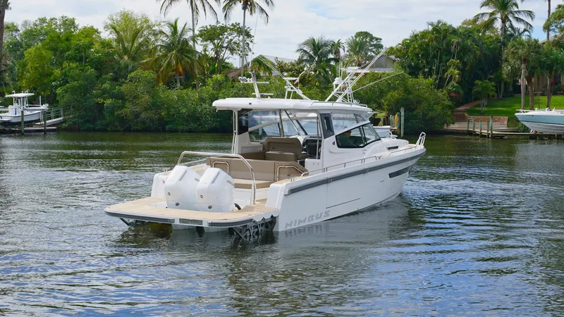 Slide: The Image of 2025 Nimbus Weekender 11 #49 boat cruising on a scenic river with lush greenery. - 2