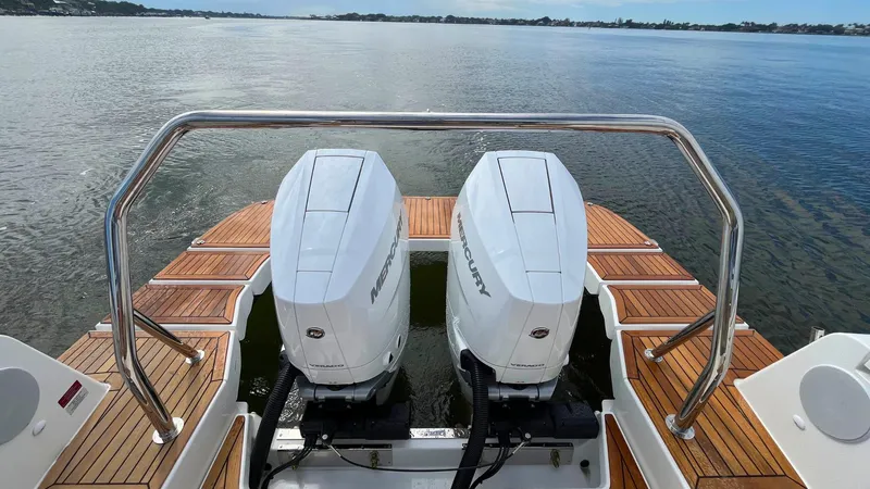 Slide: The Image of Twin Mercury outboard engines on a 2025 Nimbus Weekender 11 #49 boat, docked on calm water. - 22