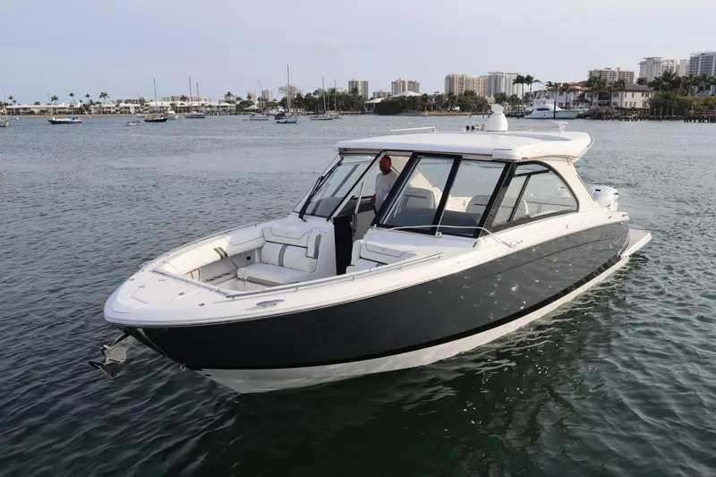 Slide: The Image of 2022 Regal LX36 boat cruising on calm waters near a coastal city. - 0