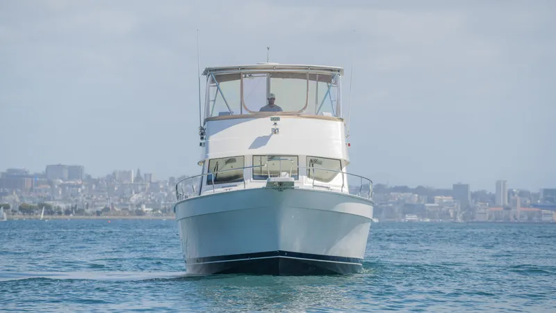 Slide: The Image of 2005 Mainship 43 Trawler Aft Cabin cruising on open water with city skyline backdrop. - 10