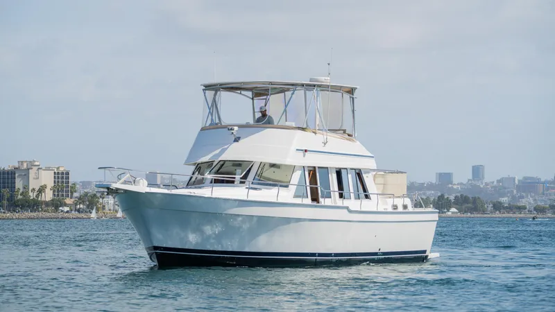 Slide: The Image of 2005 Mainship 43 Trawler Aft Cabin cruising on calm waters near city skyline. - 12
