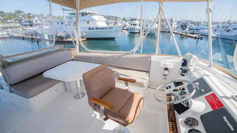 Slide: The Image of 2005 Mainship 43 Trawler Aft Cabin helm with marina view, featuring seating and steering wheel. - 15