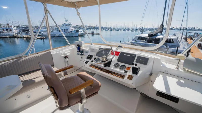 Slide: The Image of 2005 Mainship 43 Trawler Aft Cabin helm with marina view, featuring navigation controls and seating. - 16