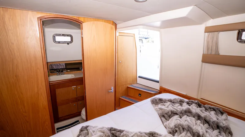 Slide: The Image of 2005 Mainship 43 Trawler Aft Cabin interior with cozy bed and wooden cabinetry. - 24