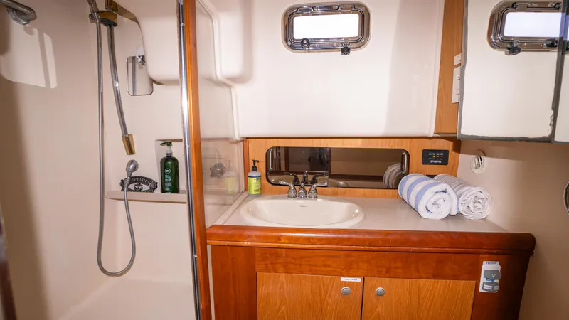 Slide: The Image of 2005 Mainship 43 Trawler Aft Cabin bathroom with shower, sink, and wooden cabinetry. - 26
