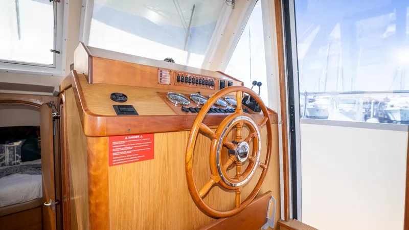 Slide: The Image of 2005 Mainship 43 Trawler Aft Cabin helm with wooden steering wheel and control panel. - 30