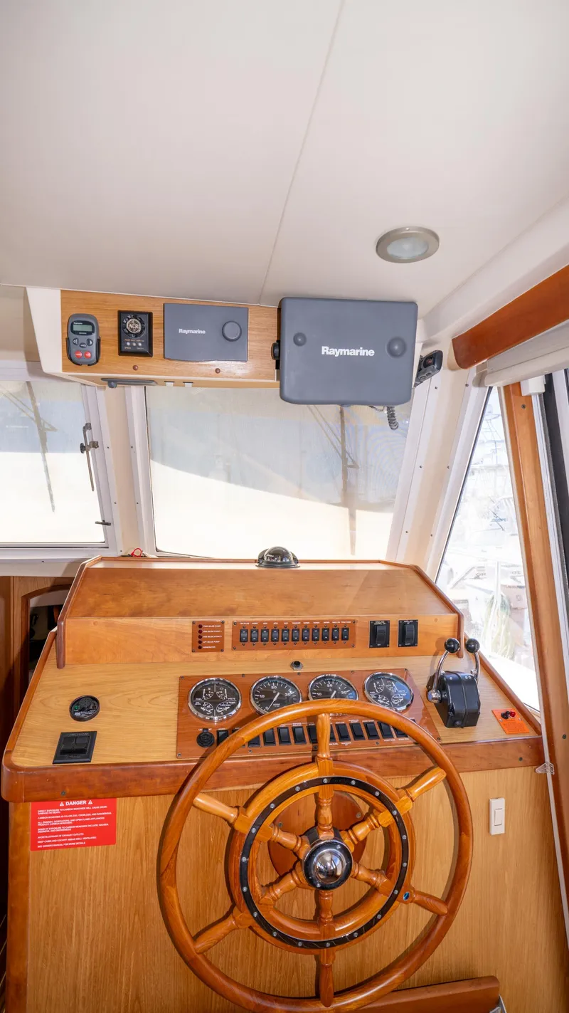 Slide: The Image of 2005 Mainship 43 Trawler Aft Cabin helm with wooden steering wheel and navigation instruments. - 34