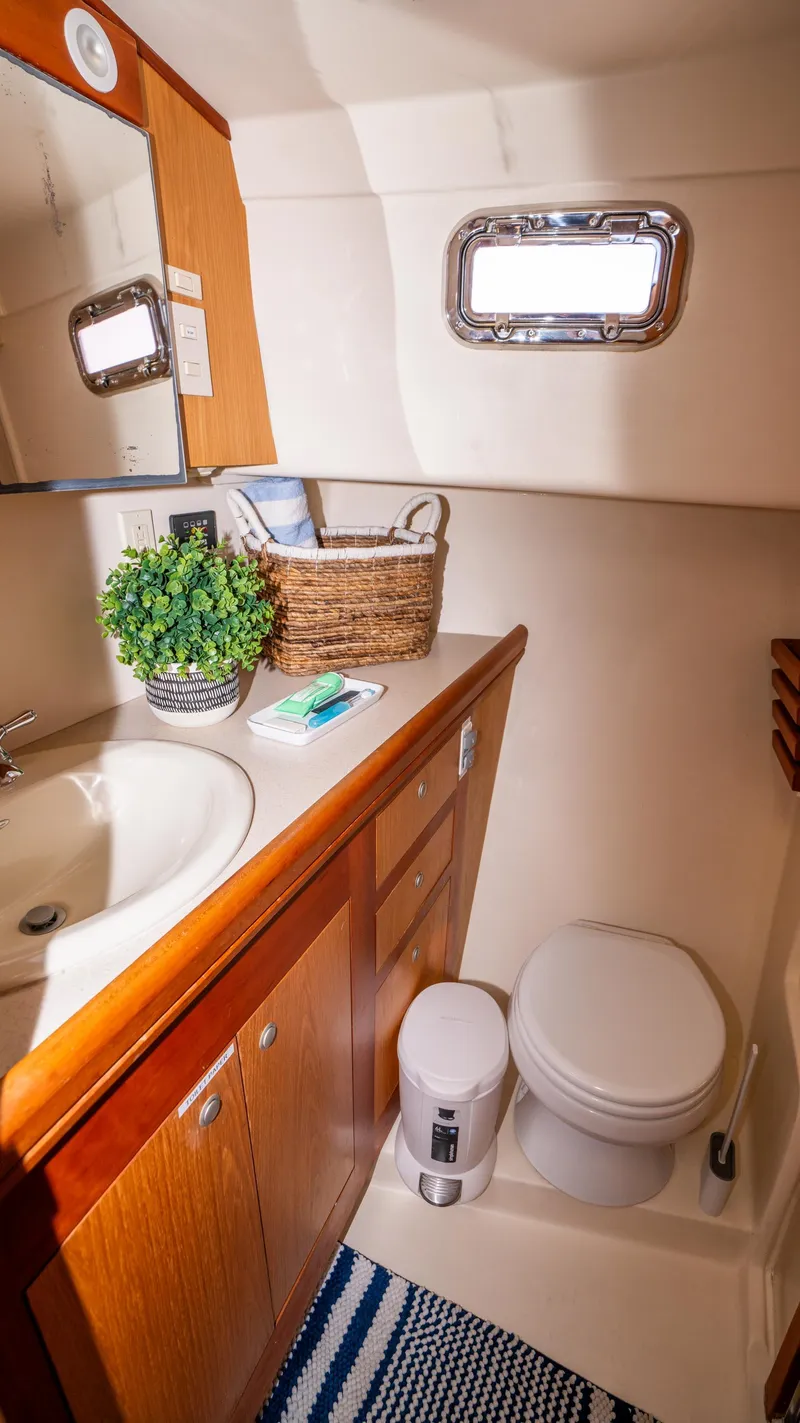 Slide: The Image of 2005 Mainship 43 Trawler Aft Cabin bathroom with sink, toilet, and porthole window. - 43