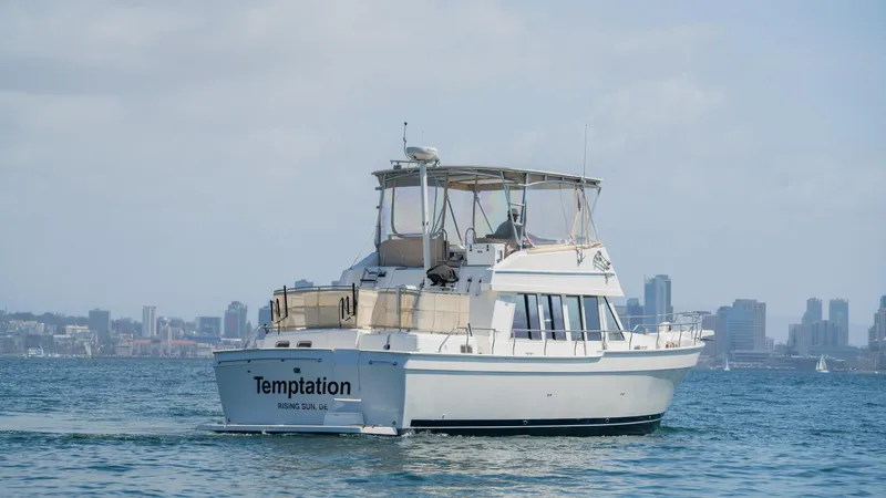 Slide: The Image of 2005 Mainship 43 Trawler Aft Cabin cruising on open water with city skyline backdrop. - 7