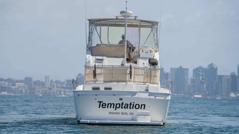 Slide: The Image of 2005 Mainship 43 Trawler Aft Cabin named "Temptation" on water with city skyline backdrop. - 8