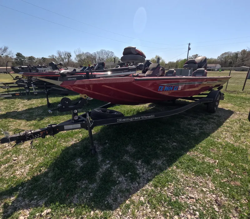 Slide: The Image of 2023 Ranger RT188 boat in red, parked on a grassy area with trailer. - 1