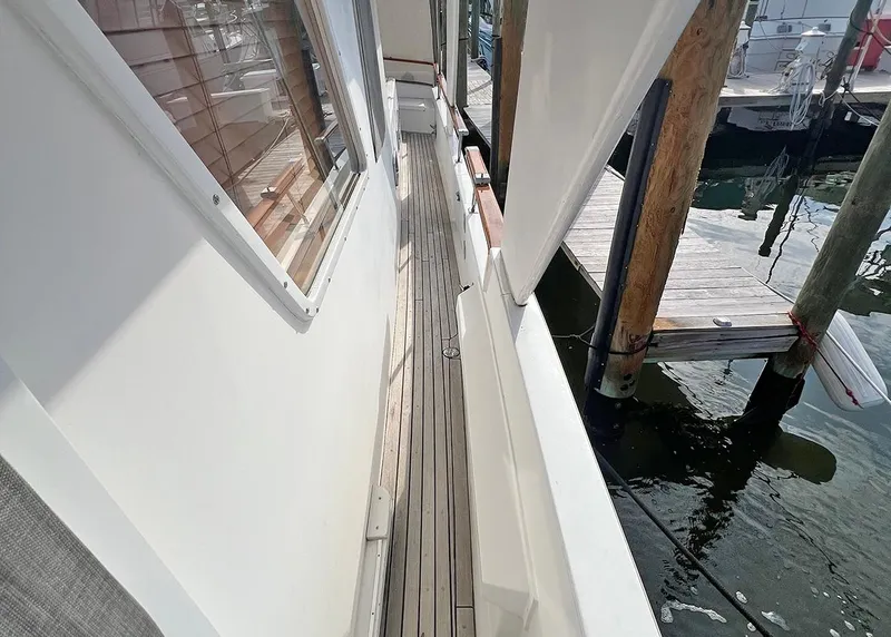 Slide: The Image of 1987 DeFever Tri-Cabin yacht side deck with wooden flooring and marina view. - 29