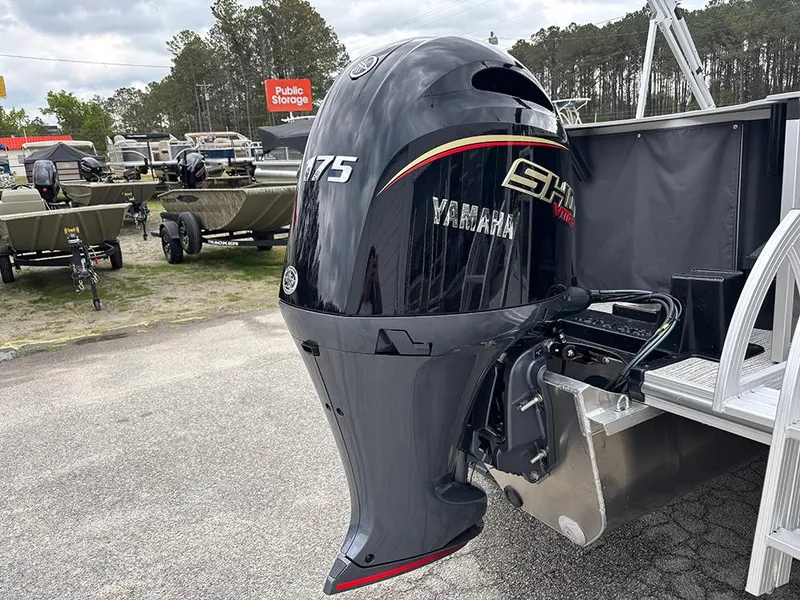 Slide: The Image of 2025 SunCatcher Select 322RF with Yamaha 175 outboard motor in a boat storage area. - 30