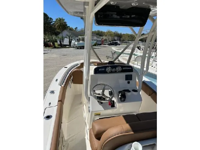 Slide: The Image of 2025 Pioneer 202 Islander boat interior with steering console and seating, parked outdoors. - 6