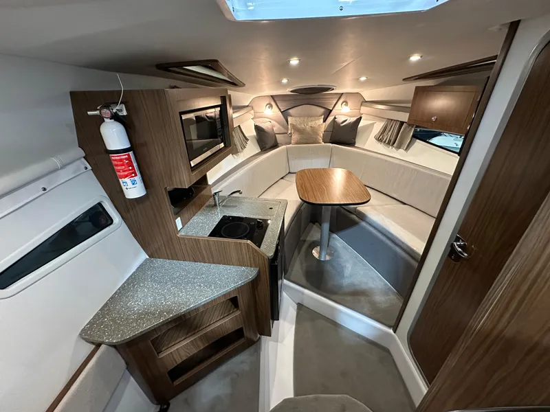 Slide: The Image of 2021 Four Winns Vista 275 cabin interior with kitchenette, seating, and table. - 15