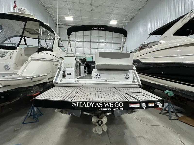 Slide: The Image of 2021 Four Winns Vista 275 boat in storage, rear view with "Steady As We Go" text. - 2